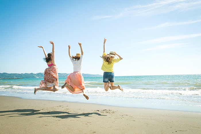 砂浜でジャンプする三人の女性